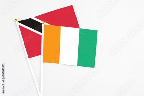 Cote D'Ivoire and Trinidad And Tobago stick flags on white background. High quality fabric, miniature national flag. Peaceful global concept.White floor for copy space.