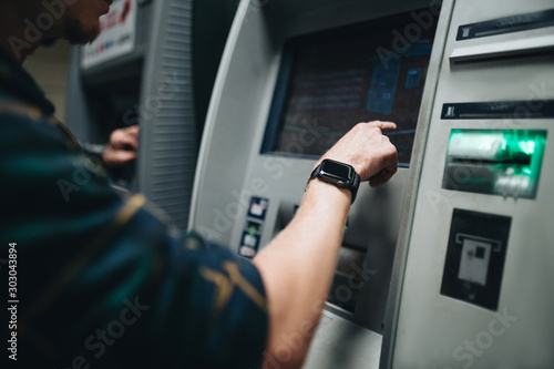 Photography Close up male hand using card with cash machine, ATM banking