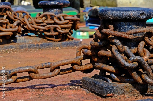 The large rusty boat anchor chain in the pile at the harbor.