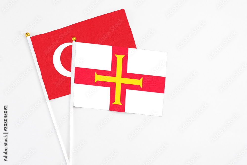 Guernsey and Turkey stick flags on white background. High quality fabric, miniature national flag. Peaceful global concept.White floor for copy space.