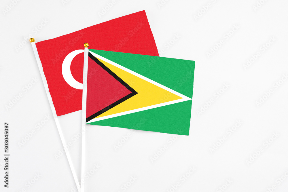 Guyana and Turkey stick flags on white background. High quality fabric, miniature national flag. Peaceful global concept.White floor for copy space.