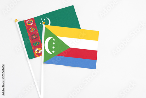 Comoros and Turkmenistan stick flags on white background. High quality fabric  miniature national flag. Peaceful global concept.White floor for copy space.