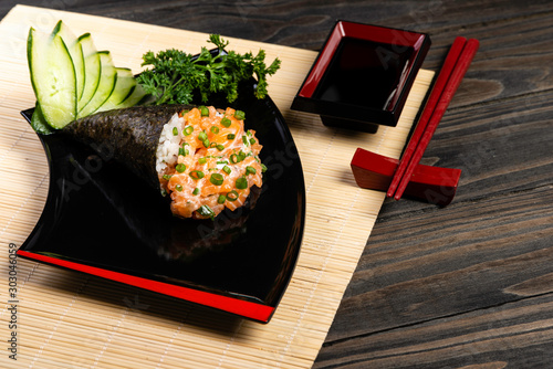 Salmon temaki sushi on black plate in black background. Japanese cuisine. photo