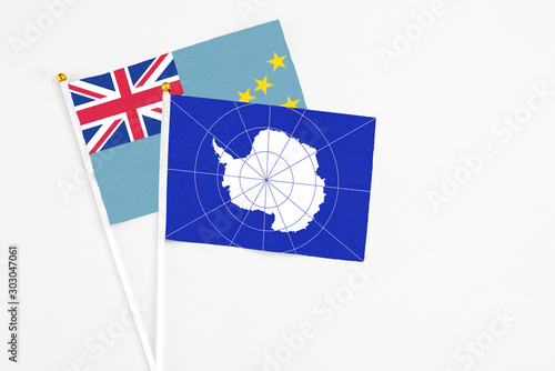 Antarctica and Tuvalu stick flags on white background. High quality fabric, miniature national flag. Peaceful global concept.White floor for copy space.