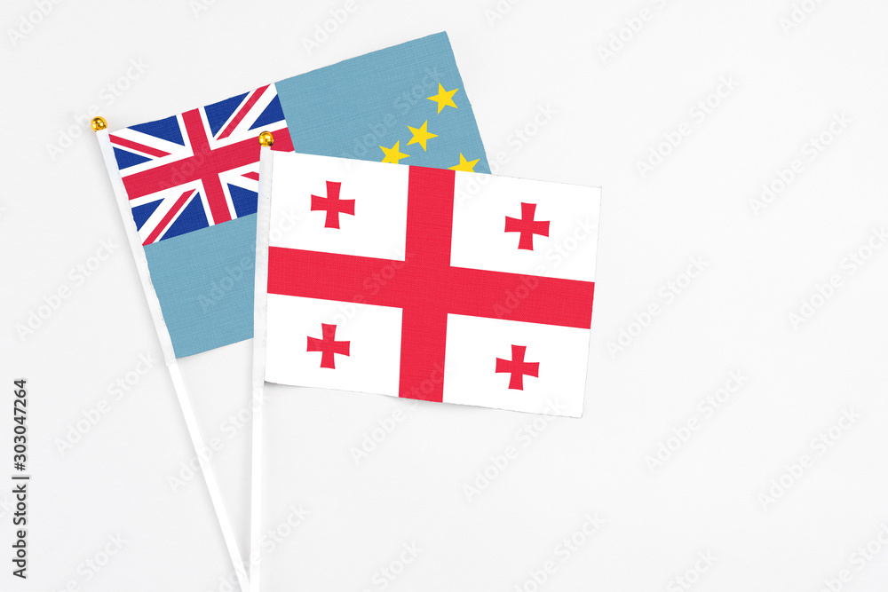 Georgia and Tuvalu stick flags on white background. High quality fabric, miniature national flag. Peaceful global concept.White floor for copy space.