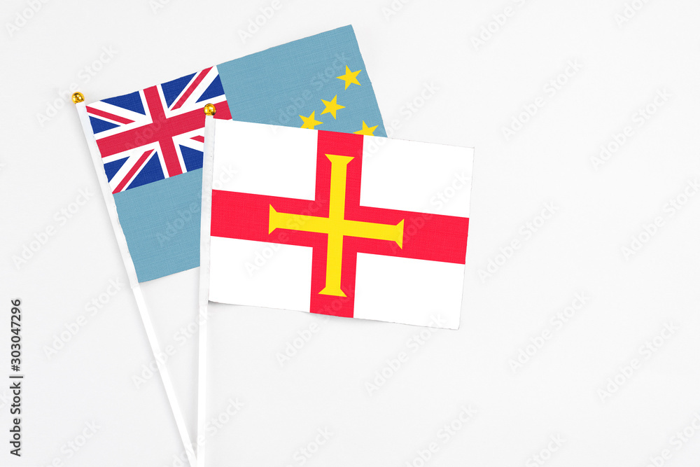Guernsey and Tuvalu stick flags on white background. High quality fabric, miniature national flag. Peaceful global concept.White floor for copy space.