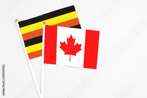 Canada and Uganda stick flags on white background. High quality fabric, miniature national flag. Peaceful global concept.White floor for copy space.