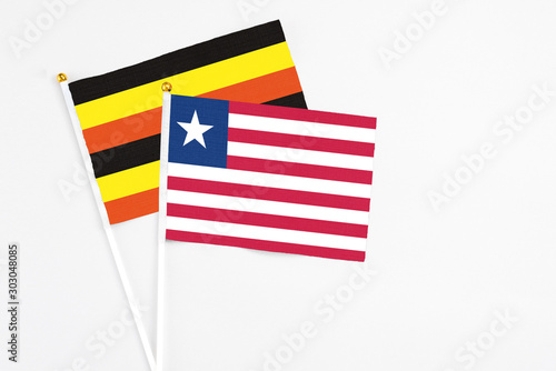 Liberia and Uganda stick flags on white background. High quality fabric, miniature national flag. Peaceful global concept.White floor for copy space.