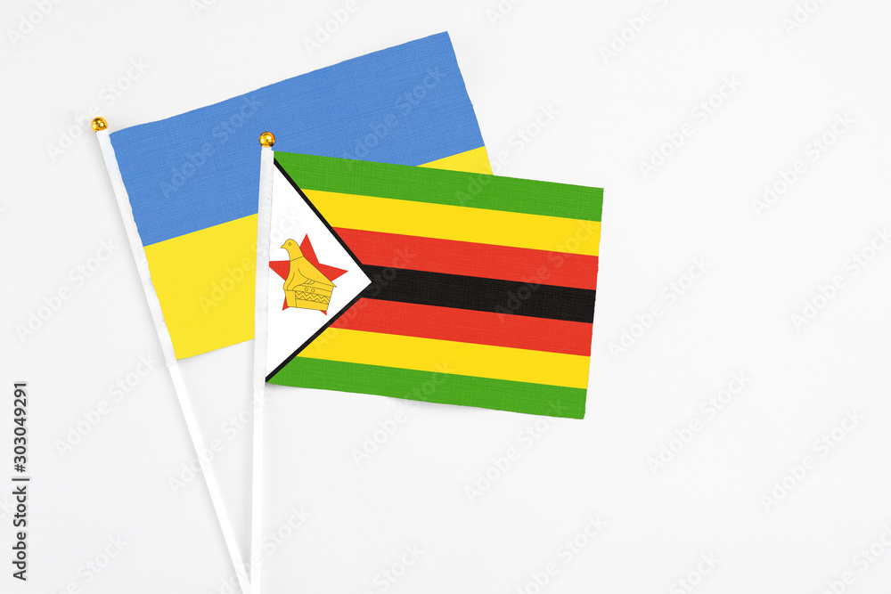 Zimbabwe and Ukraine stick flags on white background. High quality fabric, miniature national flag. Peaceful global concept.White floor for copy space. Zimbabwe and Ukraine stick flags on white background. High quality fabric, miniature national flag. Peaceful global concept.White floor for copy space.