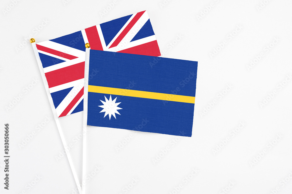Fototapeta premium Nauru and United Kingdom stick flags on white background. High quality fabric, miniature national flag. Peaceful global concept.White floor for copy space.