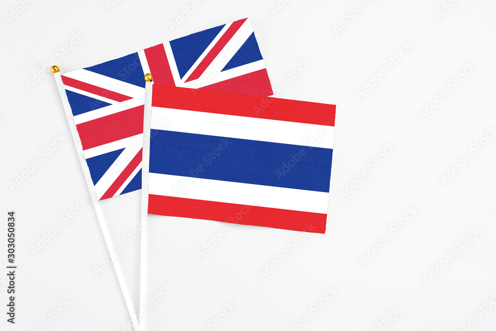Fototapeta premium Thailand and United Kingdom stick flags on white background. High quality fabric, miniature national flag. Peaceful global concept.White floor for copy space.