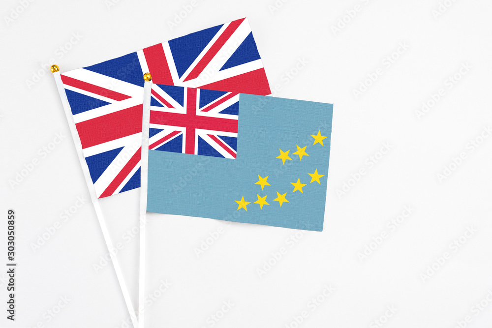 Fototapeta premium Tuvalu and United Kingdom stick flags on white background. High quality fabric, miniature national flag. Peaceful global concept.White floor for copy space.