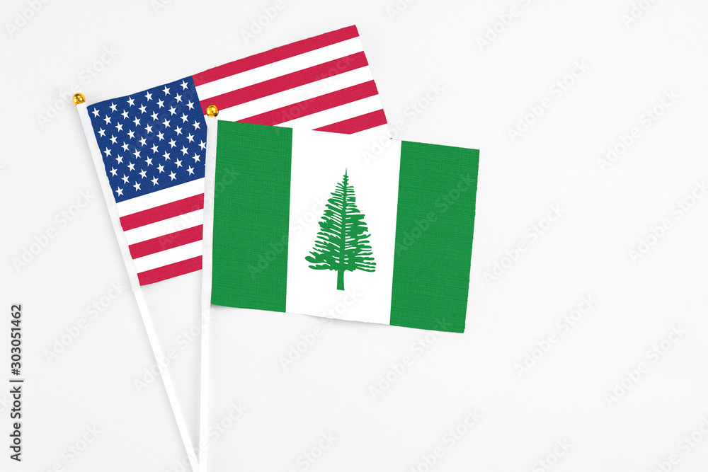 Fototapeta premium Norfolk Island and United States stick flags on white background. High quality fabric, miniature national flag. Peaceful global concept.White floor for copy space.