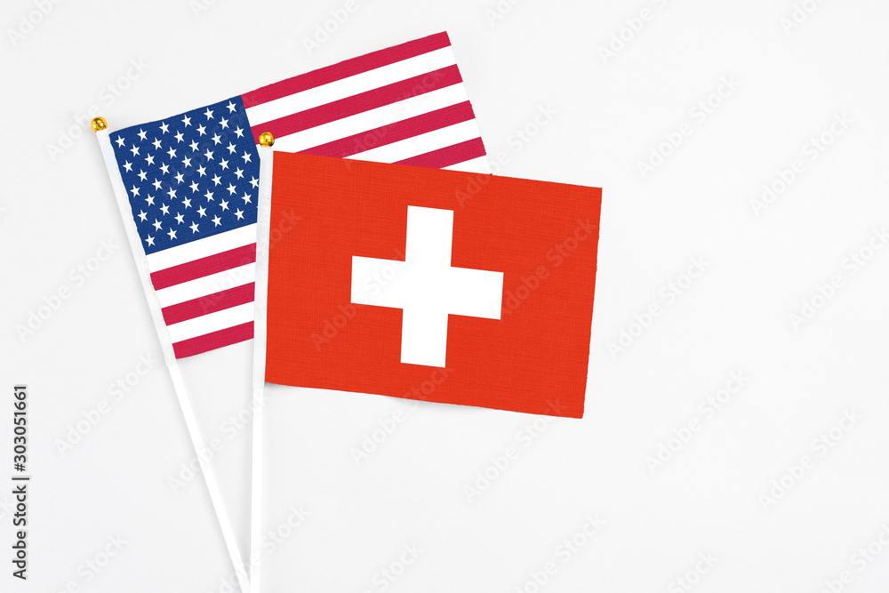 Switzerland and United States stick flags on white background. High quality fabric, miniature national flag. Peaceful global concept.White floor for copy space.