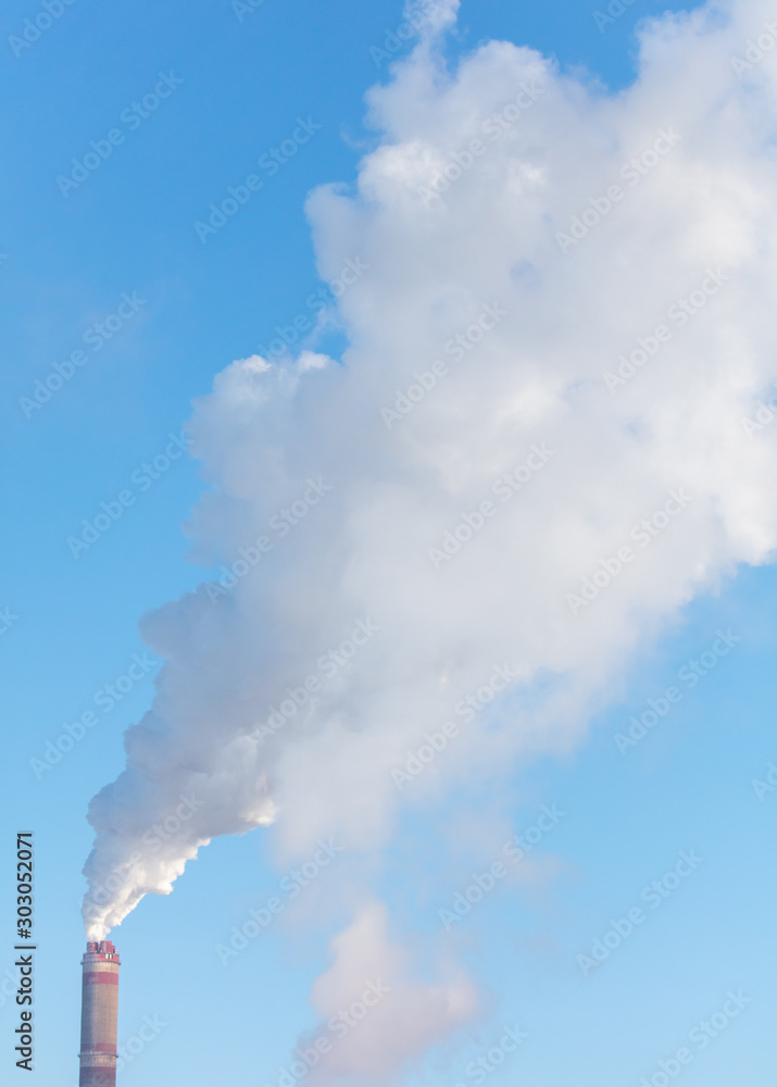 Smoke from a chimney in a factory against a blue sky