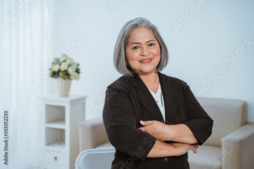 Confident senior business woman standing with crossed hands