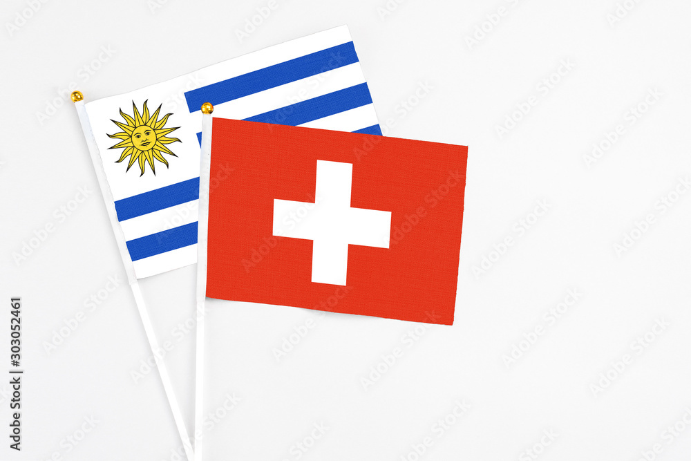Switzerland and Uruguay stick flags on white background. High quality fabric, miniature national flag. Peaceful global concept.White floor for copy space.
