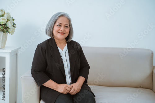 Fotografie Old woman confident is seriously beautiful sitting on couch with isolated backgr