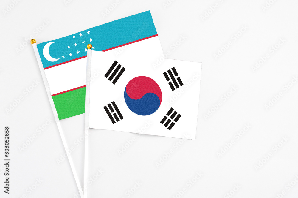 South Korea and Uzbekistan stick flags on white background. High quality fabric, miniature national flag. Peaceful global concept.White floor for copy space.