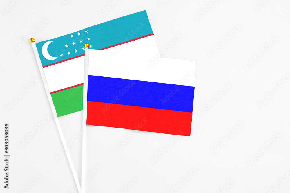 Russia and Uzbekistan stick flags on white background. High quality fabric, miniature national flag. Peaceful global concept.White floor for copy space. Russia and Uzbekistan stick flags on white background. High quality fabric, miniature national flag. Peaceful global concept.White floor for copy space.