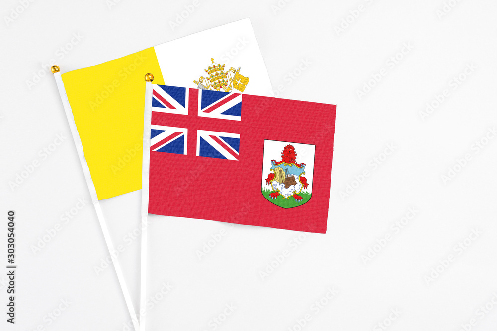 Fototapeta premium Bermuda and Vatican City stick flags on white background. High quality fabric, miniature national flag. Peaceful global concept.White floor for copy space.