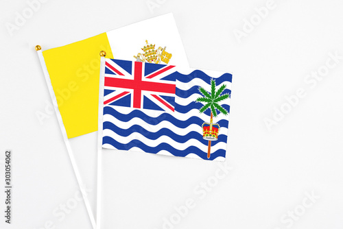 British Indian Ocean Territory and Vatican City stick flags on white background. High quality fabric, miniature national flag. Peaceful global concept.White floor for copy space. photo