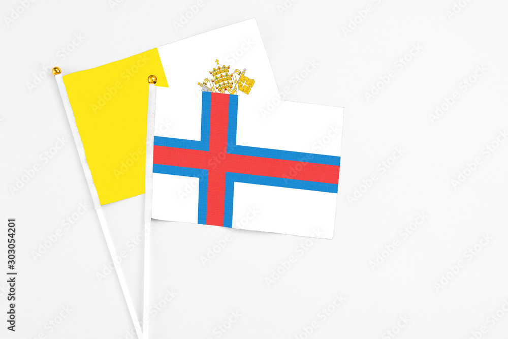 Faroe Islands and Vatican City stick flags on white background. High quality fabric, miniature national flag. Peaceful global concept.White floor for copy space.