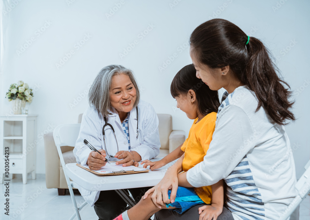 Female doctor records complaints of pain from children who use the clipboard Female doctor records complaints of pain from children who use the clipboard