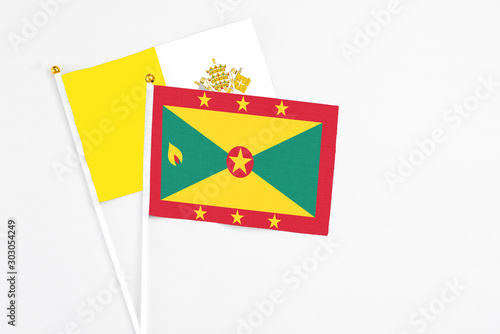 Grenada and Vatican City stick flags on white background. High quality fabric, miniature national flag. Peaceful global concept.White floor for copy space.