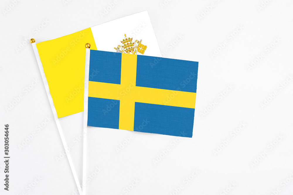 Sweden and Vatican City stick flags on white background. High quality fabric, miniature national flag. Peaceful global concept.White floor for copy space.