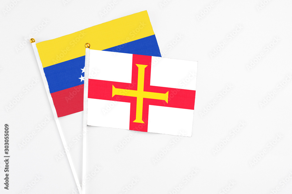 Guernsey and Venezuela stick flags on white background. High quality fabric, miniature national flag. Peaceful global concept.White floor for copy space.