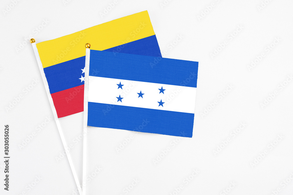 Fototapeta premium Honduras and Venezuela stick flags on white background. High quality fabric, miniature national flag. Peaceful global concept.White floor for copy space.
