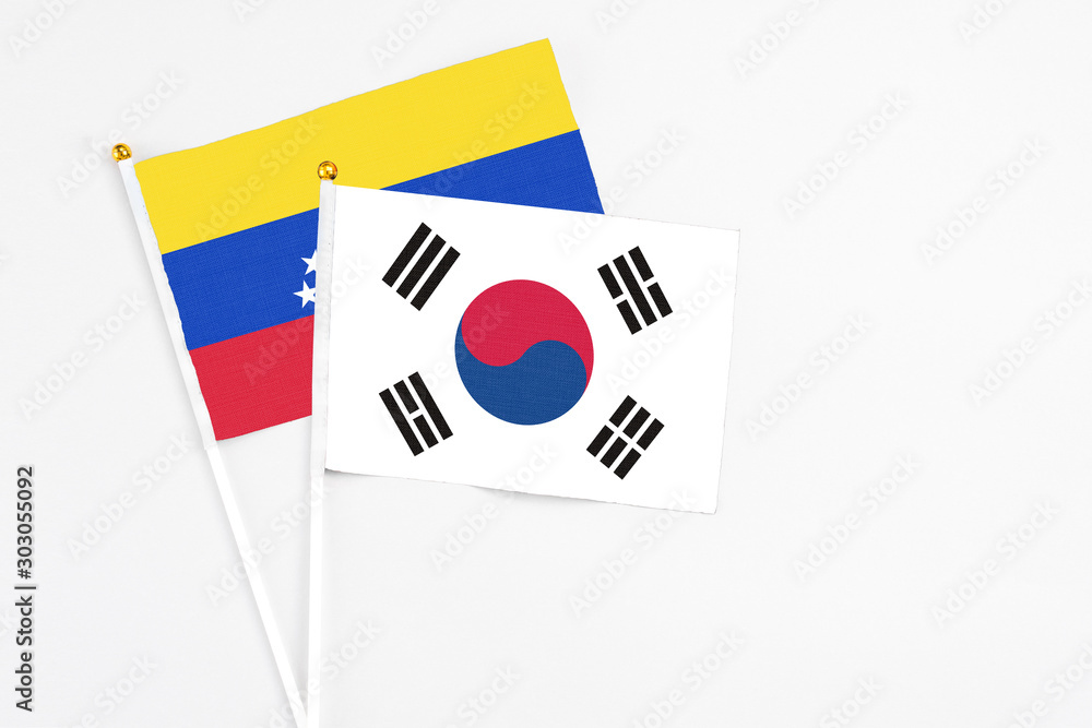 South Korea and Venezuela stick flags on white background. High quality fabric, miniature national flag. Peaceful global concept.White floor for copy space.