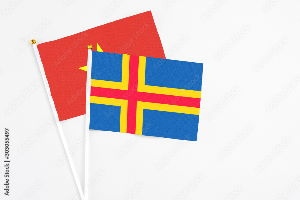 Aland Islands and Vietnam stick flags on white background. High quality fabric, miniature national flag. Peaceful global concept.White floor for copy space.