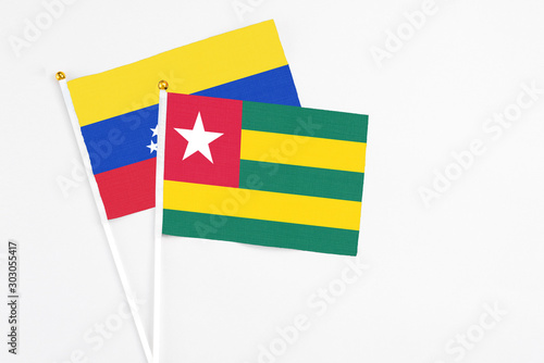 Togo and Venezuela stick flags on white background. High quality fabric  miniature national flag. Peaceful global concept.White floor for copy space.