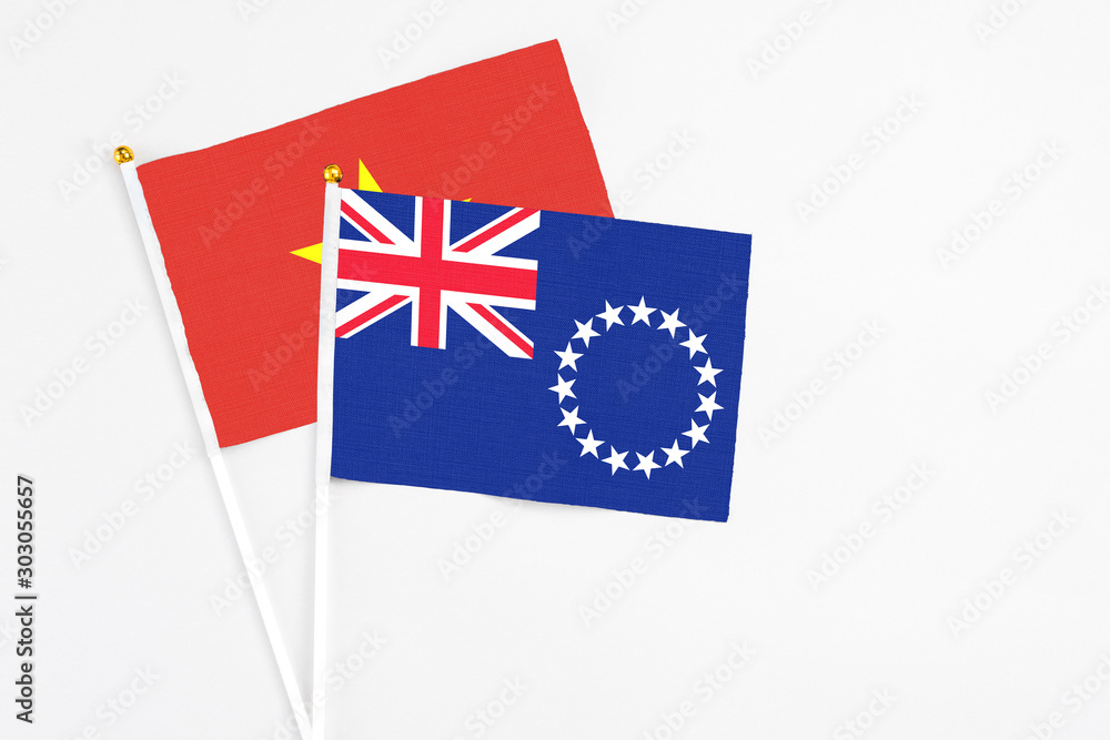 Fototapeta premium Cook Islands and Vietnam stick flags on white background. High quality fabric, miniature national flag. Peaceful global concept.White floor for copy space.