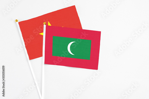 Maldives and Vietnam stick flags on white background. High quality fabric, miniature national flag. Peaceful global concept.White floor for copy space.