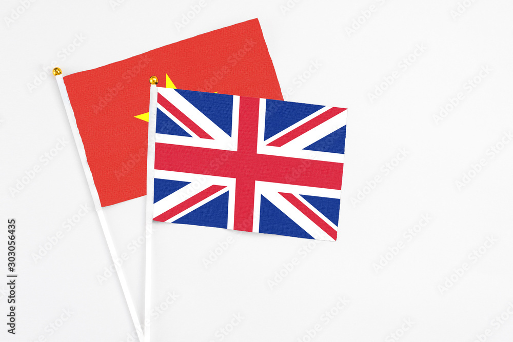 Fototapeta premium United Kingdom and Vietnam stick flags on white background. High quality fabric, miniature national flag. Peaceful global concept.White floor for copy space.