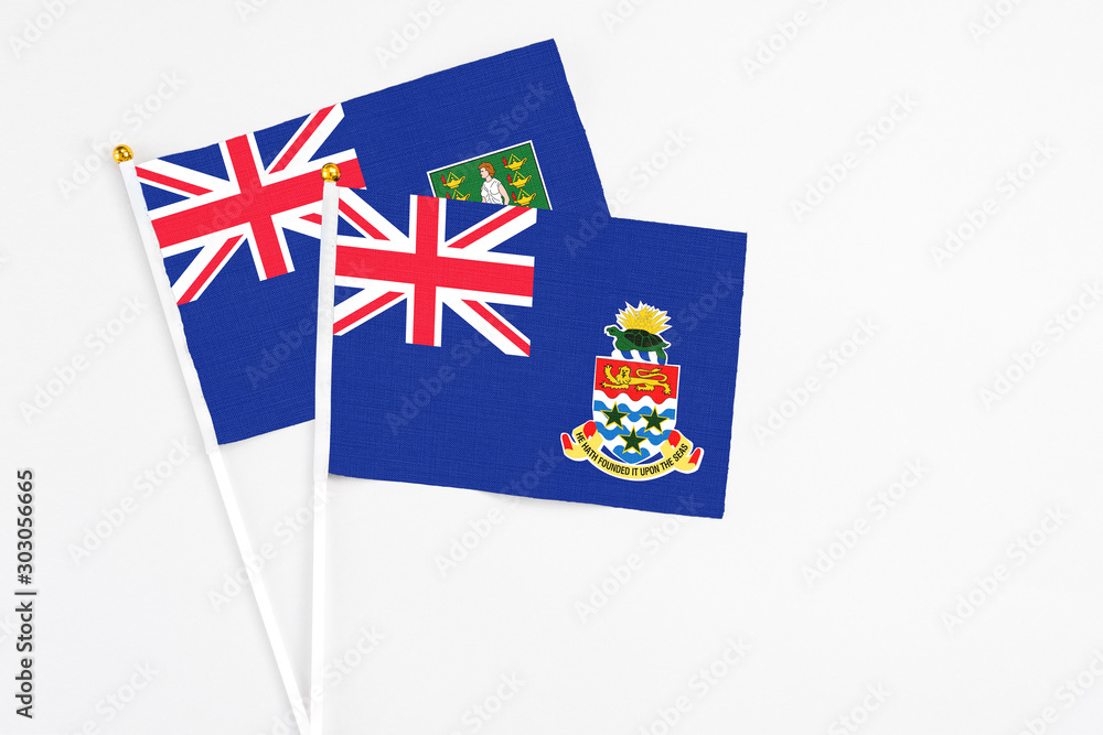 Fototapeta premium Cayman Islands and British Virgin Islands stick flags on white background. High quality fabric, miniature national flag. Peaceful global concept.White floor for copy space.