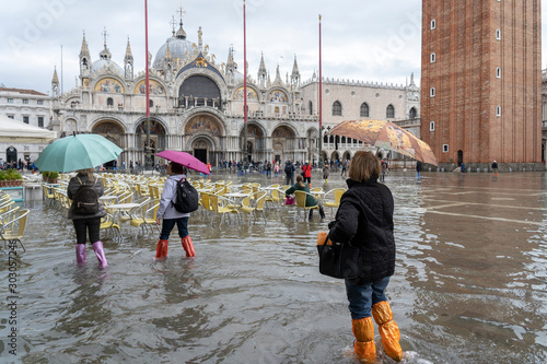 VENICE, ITALY - November 12, 2019: St. Marks Square (Piazza San Marco) during flood (acqua alta) in Venice, Italy. Venice high water. Tourists at St. Mark's Square during high water photo