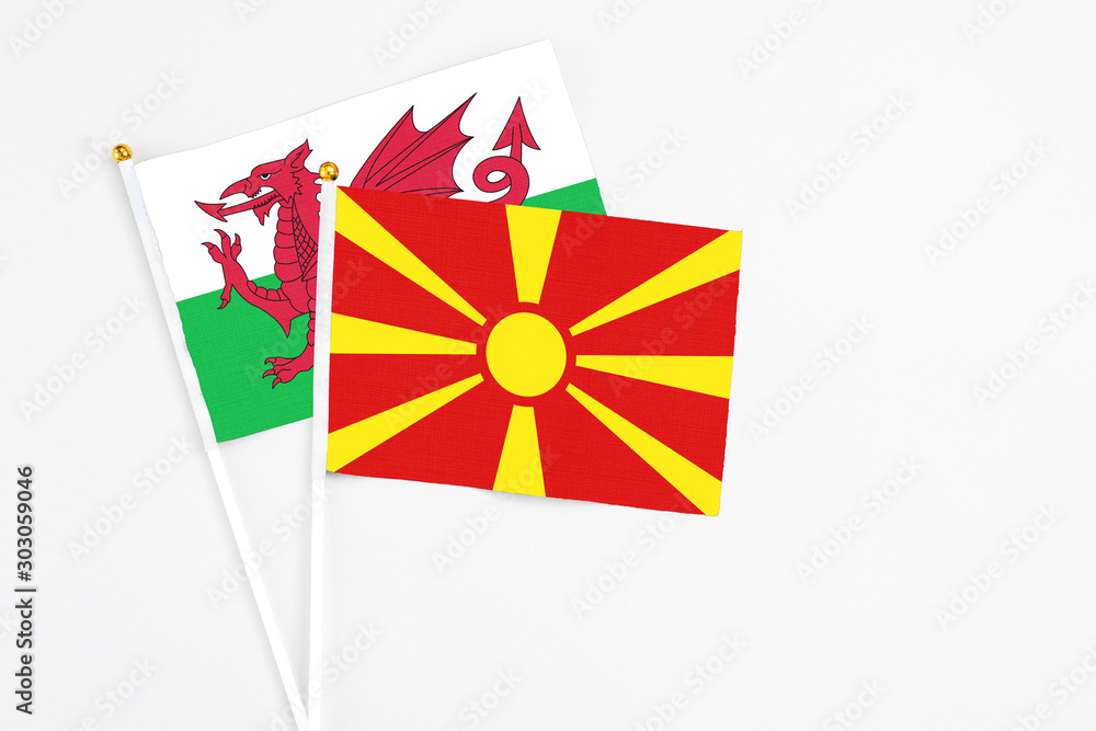 Macedonia and Wales stick flags on white background. High quality fabric, miniature national flag. Peaceful global concept.White floor for copy space.