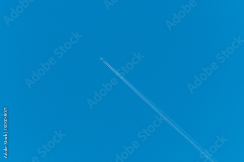 Jet airliner flying high in the sky leaves contrails in the clear blue sky 