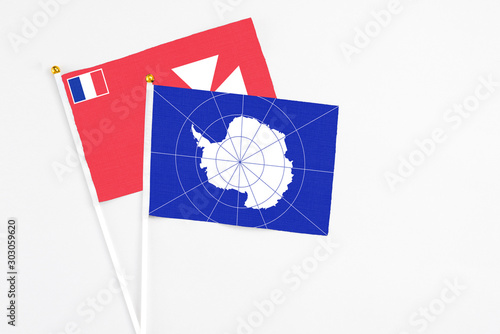 Antarctica and Wallis And Futuna stick flags on white background. High quality fabric, miniature national flag. Peaceful global concept.White floor for copy space.