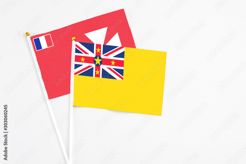 Niue and Wallis And Futuna stick flags on white background. High quality fabric, miniature national flag. Peaceful global concept.White floor for copy space. Niue and Wallis And Futuna stick flags on white background. High quality fabric, miniature national flag. Peaceful global concept.White floor for copy space.