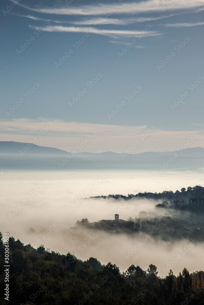 Surreal view of of a little town in Umbria (Italy) almost completely hidden by fog