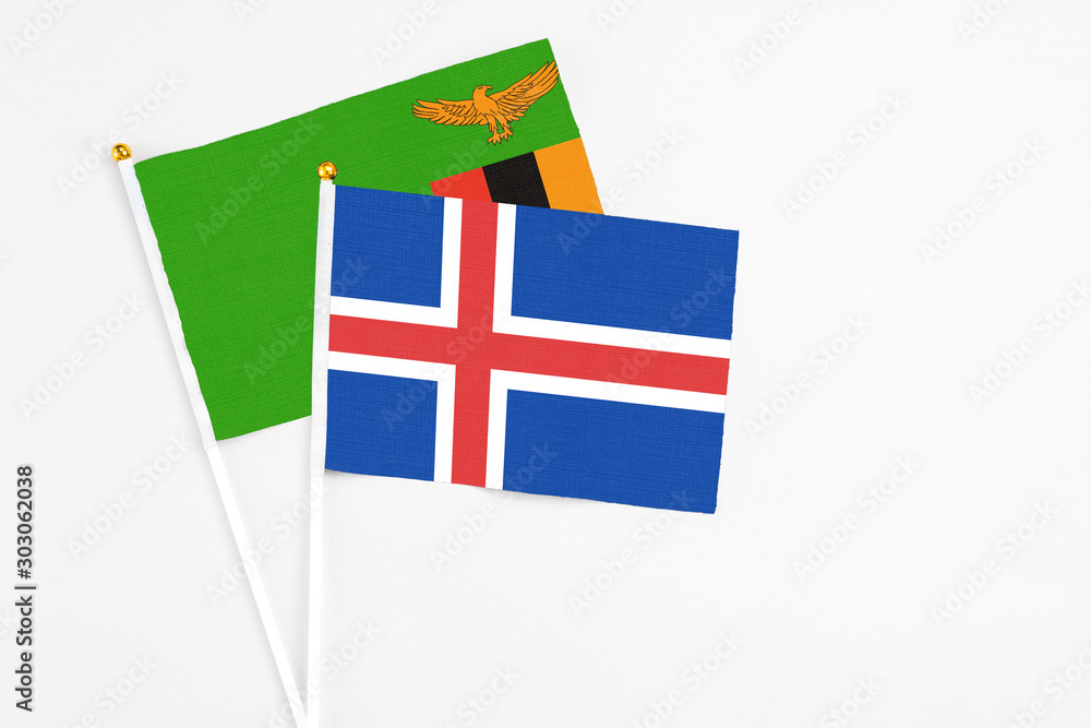 Iceland and Zambia stick flags on white background. High quality fabric, miniature national flag. Peaceful global concept.White floor for copy space.