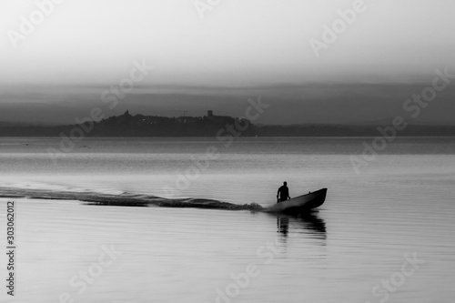 Trasimeno lake at sunset with a man on a little boat