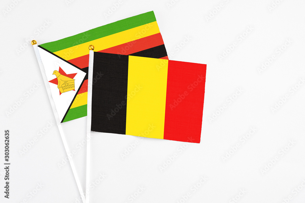 Belgium and Zimbabwe stick flags on white background. High quality fabric, miniature national flag. Peaceful global concept.White floor for copy space.
