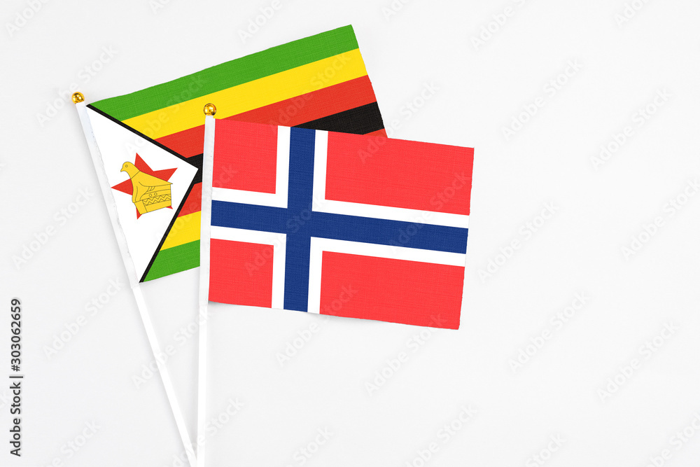 Bouvet Islands and Zimbabwe stick flags on white background. High quality fabric, miniature national flag. Peaceful global concept.White floor for copy space.