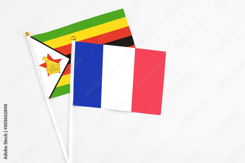 France and Zimbabwe stick flags on white background. High quality fabric, miniature national flag. Peaceful global concept.White floor for copy space.